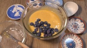 Smooth cake batter in a glass bowl with fresh blueberries added on top