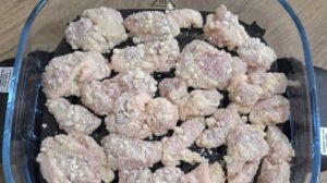 Coated chicken pieces laid out in the air fryer basket before cooking