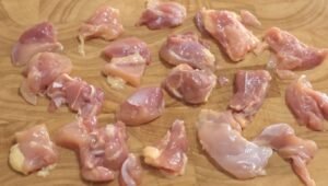 Chicken thigh cut into small cubes on a cutting board