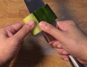 Rolling a cucumber against a knife to cut thin sheets for matchsticks