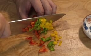 Diced red, yellow, and green bell peppers on a cutting board