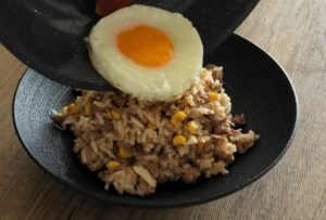 Placing a fried egg on top of the soy garlic beef rice