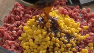 Soy garlic marinade poured over raw minced beef and sweet corn