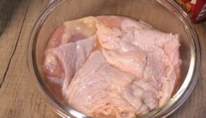 Chicken thighs marinating in a glass bowl
