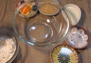 Ingredients for mini blueberry cakes: egg, sugar, olive oil, milk and flour in small bowls