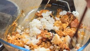 Mixing cooked rice into the gochujang chicken and cabbage in the air fryer