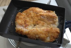 Chicken thigh frying in a skillet