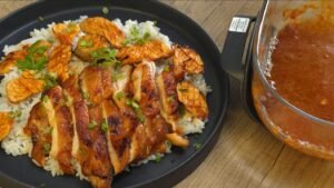 Gochujang chicken and mushrooms plated over rice with extra sauce drizzled on top