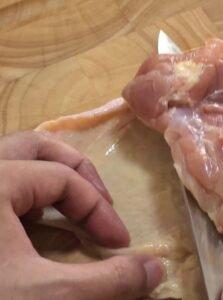 Separating the skin from a chicken thigh with a knife