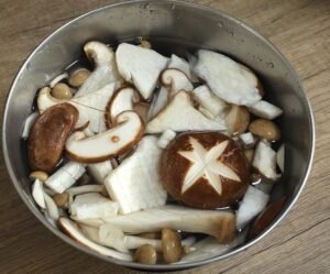 Scored shiitake, shimeji and king oyster mushrooms in a bowl
