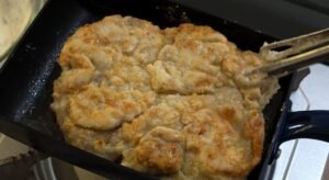 Searing floured chicken thigh until golden in a skillet