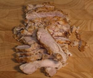 Sliced chilled chicken thigh on a cutting board