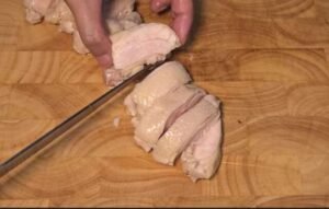 Slicing poached chicken thigh into thick pieces