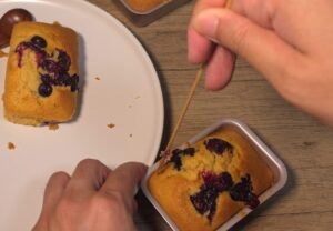 Testing a baked mini blueberry cake with a wooden skewer