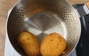 Two potatoes boiling in a small pot for mashed potatoes