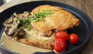 Pan-seared chicken thigh with creamy Swiss brown mushroom sauce, mashed potato, baby corn and cherry tomatoes