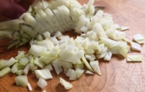 Finely diced onion on a wooden chopping board