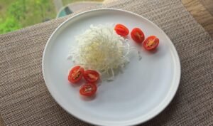 Shredded cabbage and halved cherry tomatoes arranged on a white plate
