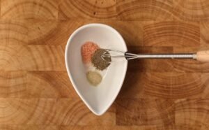 Salt, black pepper and white pepper seasoning mix in a small white bowl